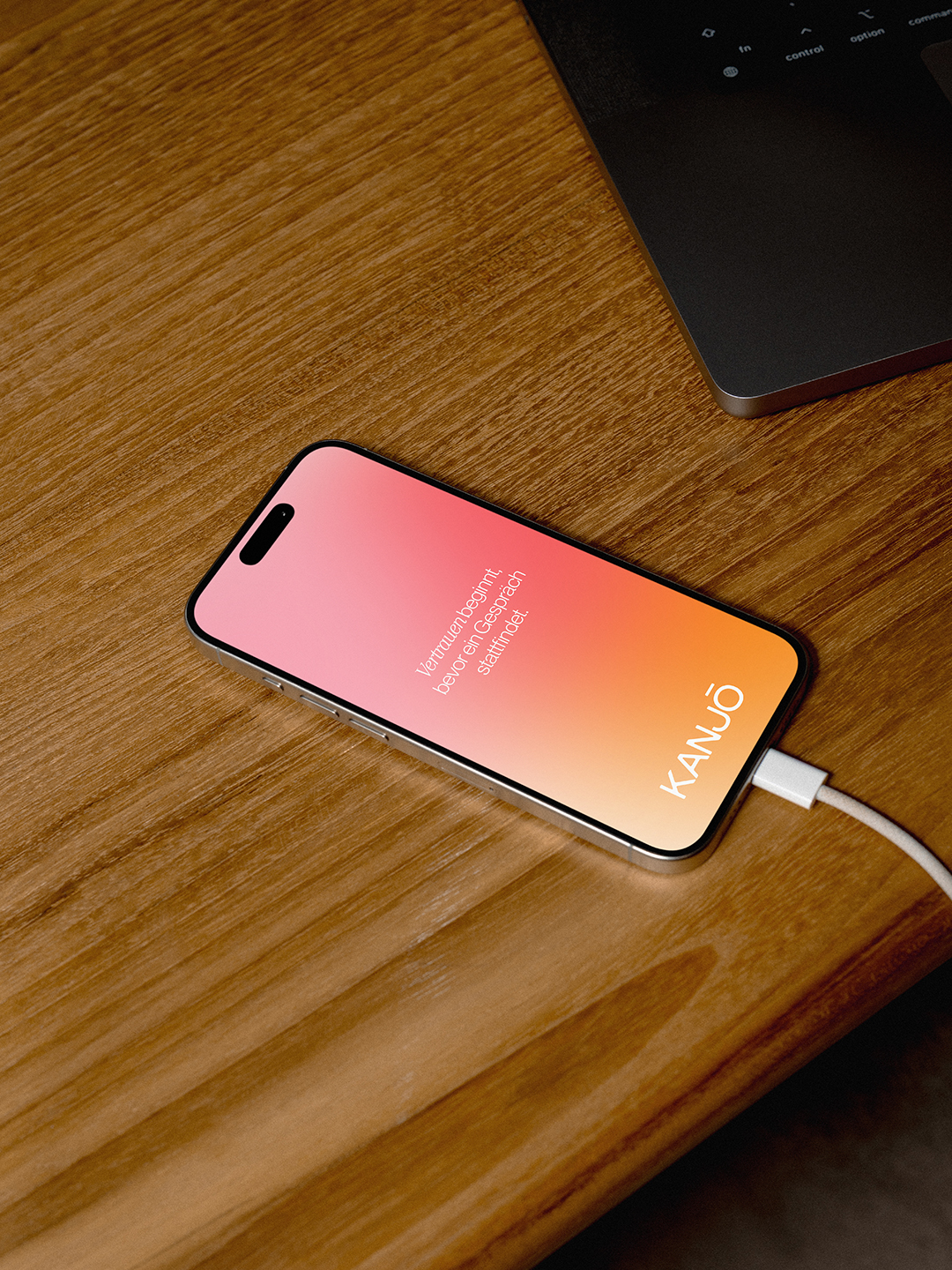 Smartphone mit rosa-orangem Kanjō-Design auf einem Holztisch – Webdesign für Praxis Kanjō